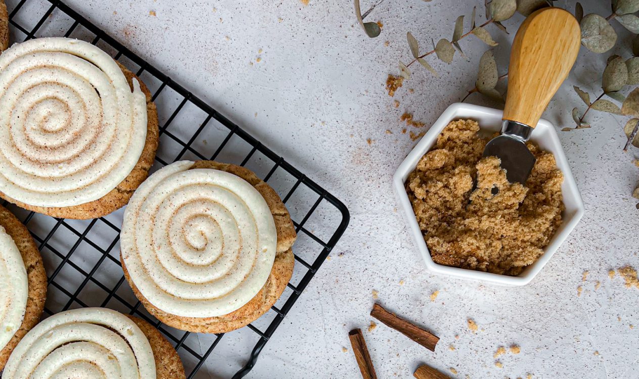Soft snickerdoodle froseted cake cookies on a cooling tray with crushed cookies beside